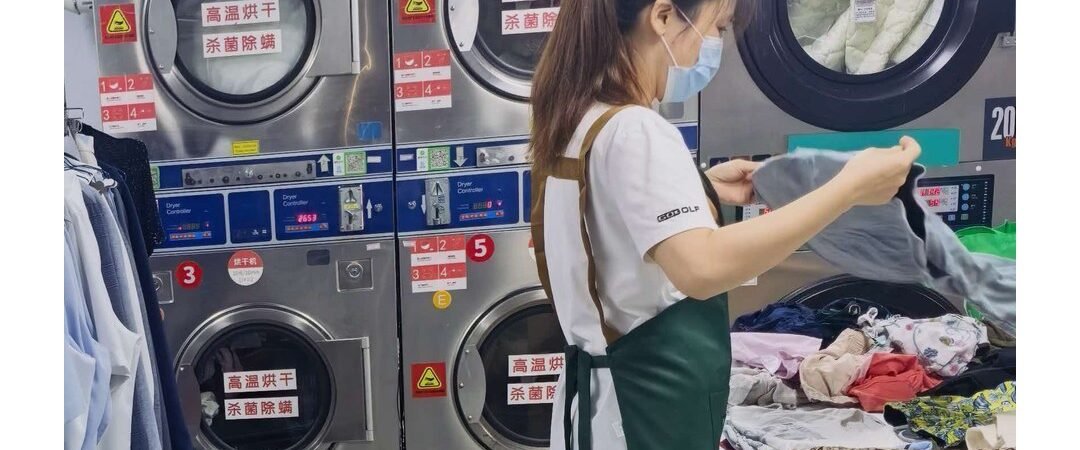 Easy Life Laundry team member sorting clothes beside the dryers, Xishuangbanna
